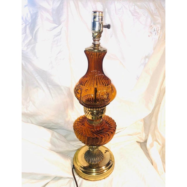 Vintage 60’s amber glass lamp with brass base and brass decorative accents. Light gray felt bottom with original electric...