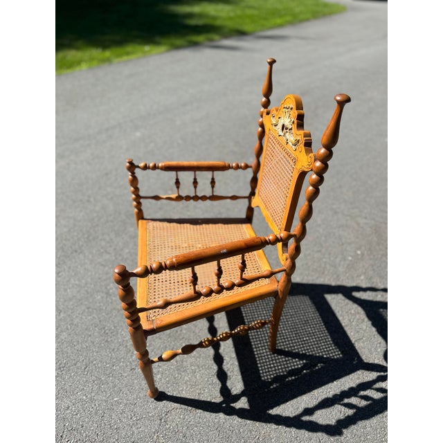 vintage Jacobean style bobbin armchair, likely from the 1900s, featuring a caned seat and backrest, and distinctive...