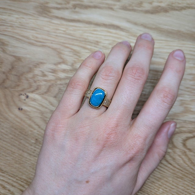 A Sonoran turquoise shines in a robin's-egg blue at the heart of this solid 14K yellow gold ring, framed by forty-eight...