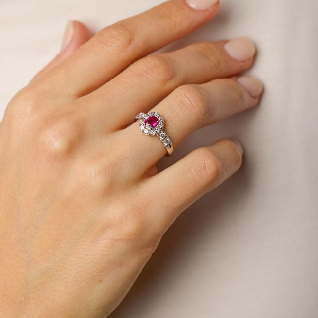 This refined vintage cluster ring showcases a richly colored oval ruby at its center, its warm hue drawing the eye with...