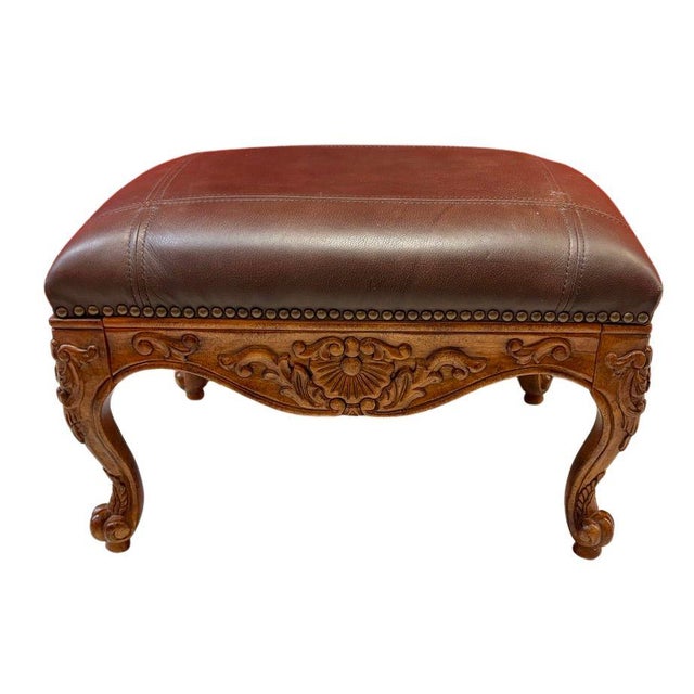 Vintage Louis XV-style footstool featuring an ornately carved wood frame, cabriole legs, floral and foliate decoration,...