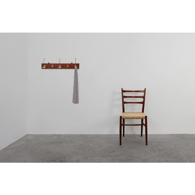 A refined French Art Nouveau wall-mounted coat rack from around 1900, combining sculptural brass hooks with a richly toned...