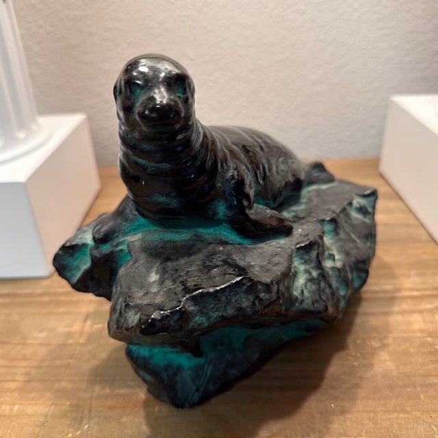 Sea-lion atop a rock island. Made from earthenware it’s quite heavy. Beautiful glassy deep green glazing.