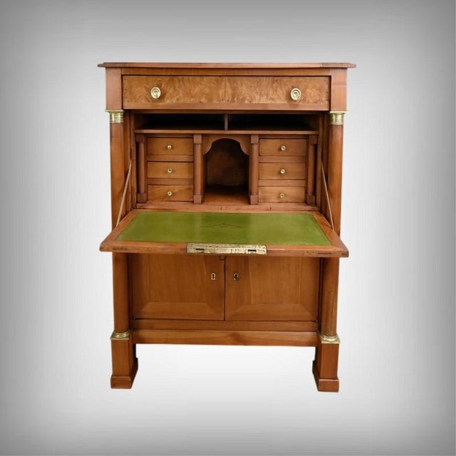 This Empire secretary desk is crafted from cherry wood with a burr elm veneer front. At the top, a drawer in the frieze...