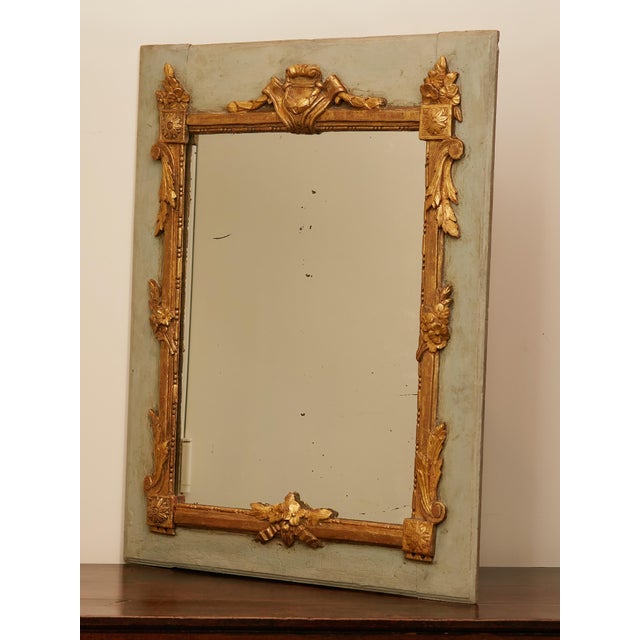 A French painted and carved giltwood mirror from the early 19th century, with cartouche, flowers and foliage motifs....