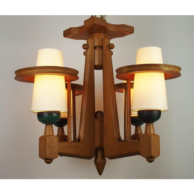 Light-colored solid oak chandelier with four lights adorned with black and green ceramic cups by Boleslaw Danikowski....