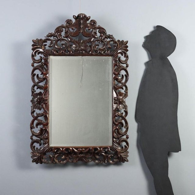 Baroque style mirror crafted from intricately carved and pierced wood with volutes and scrolls, showcasing the artisanal...