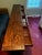 An antiqued wood console table, with four frieze drawers and two further tiers between square tapering supports. Need to...
