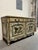 French Provincial style sideboard featuring a distressed painted finish and decorative floral panels. Two cabinet doors...