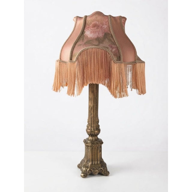 A beautiful vintage table lamp with an ornate neoclassical column base, softly aged bronze-toned finish, and an elaborate...