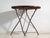 This antique folding garden table in wood and iron is a bistro table with a round slatted top and a folding iron base. It...