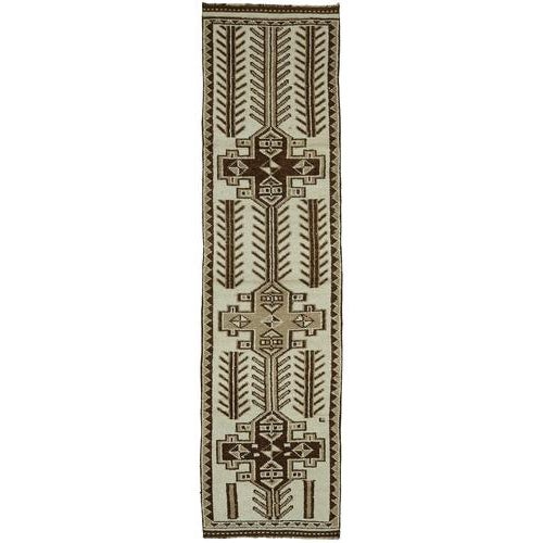 This exquisite runner rug is a rare example of tribal craftsmanship, hand-knotted by the women of the Herki tribe during...