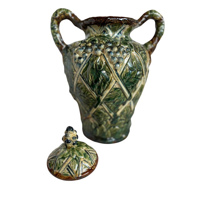 Mid 20th century lidded urn with handles, featuring a richly detailed majolica grapevine motif. The glazed surface carries...