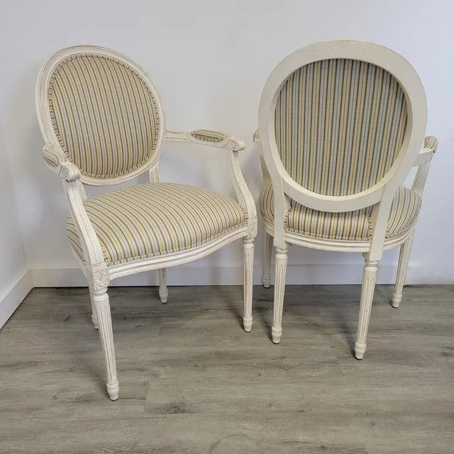 A refined pair of Louis XVI–style armchairs by Ethan Allen, featuring oval backs, fluted legs, and delicately carved...