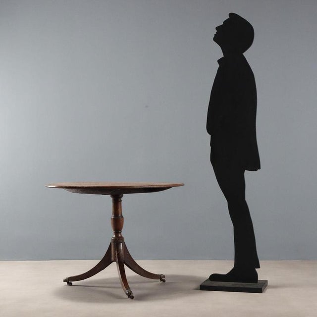 Mahogany sail table. Oval top supported by a turned leg resting on three saber-shaped feet, culminating in bronze cups and...