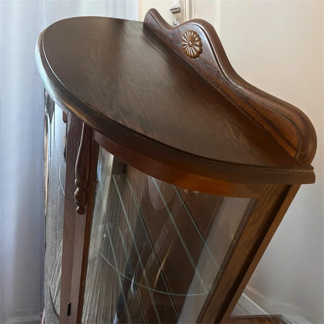 Beautiful compact oak curio cabinet featuring curved glass panels, three adjustable glass shelves, and a working interior...