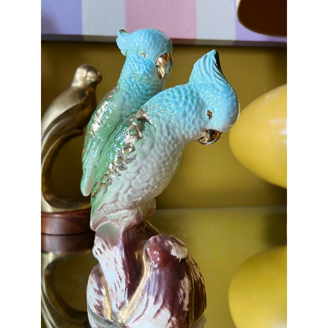 Glazed ceramic sculpture depicting two parrots perched on a stylized tree branch, dating to the 1920s. The surface...
