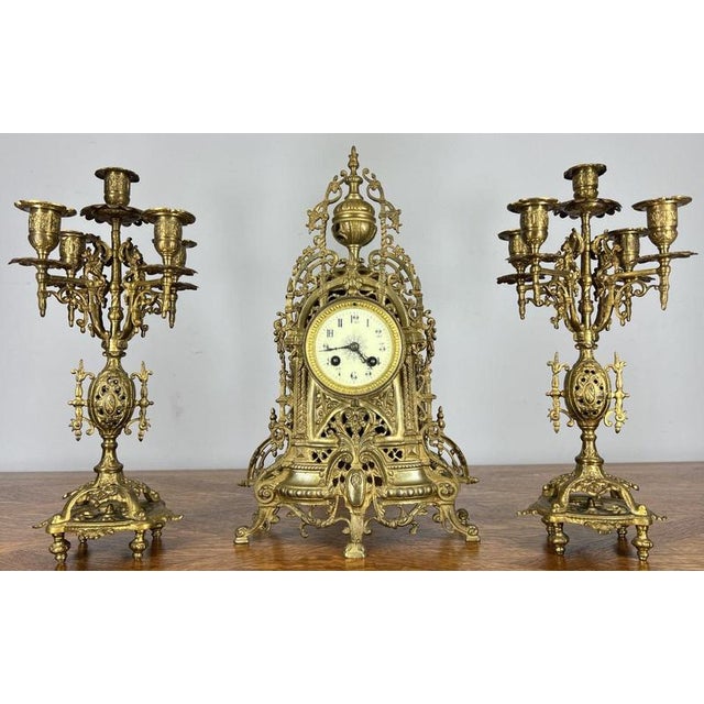 This striking Vintage French mantel clock garniture features an architectural openwork brass design, paired with a...