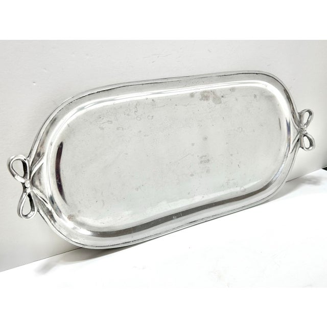 A charming vintage aluminum serving tray with sculptural bow handles, perfect for Hollywood Regency styling,...