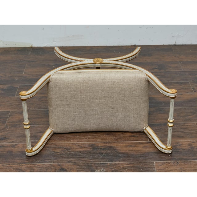 With its sweeping curule base and refined ornamentation, this French Neoclassical-style stool echoes the grandeur of...