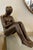 Bronze sculpture by Mimmo Paladino depicting a human figure crouching on the ground. The sculpture is highly expressive,...