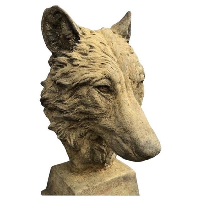 A striking cast stone bust depicting the head of a wolf with strong sculptural detailing and an attractively weathered...