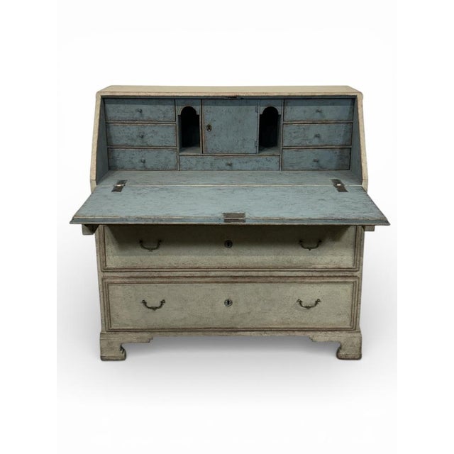 A classic Swedish antique secretary in a warm shade of beige. The lid and all drawer fronts feature a subtle frame running...