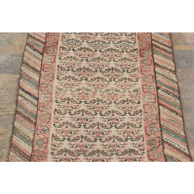 Handwoven in wool, circa 1900–1920, this antique 2x12 Kurdish runner rug features a richly patterned field with repeating...