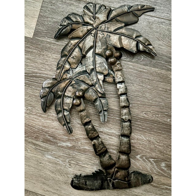 Vintage metal wall art sculpture of two overlapping palm trees with an antiqued bronze finish.