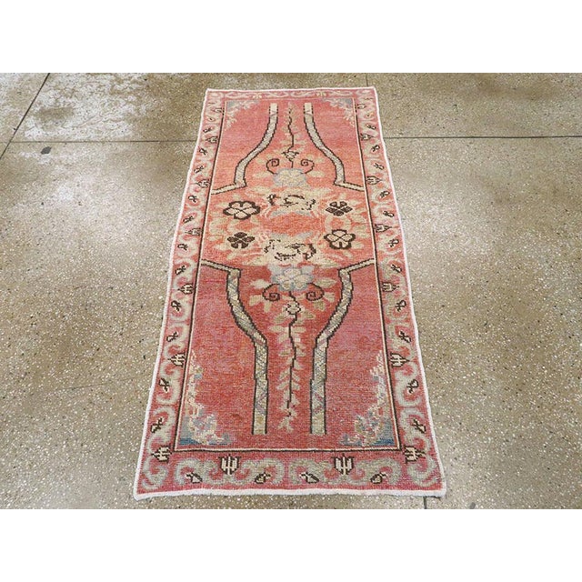 This mid-20th century Turkish Oushak rug, displays a graceful and highly stylized floral arrangement set against a warm,...
