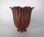 A fluted floriform copper vase with a distinctive red patina and a flaring rim on a small pedestal foot by noted American...