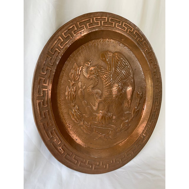 Large round Mexican mid century solid copper wall plaque, with hand hammered Mexican eagle emblem at center and Greek key...