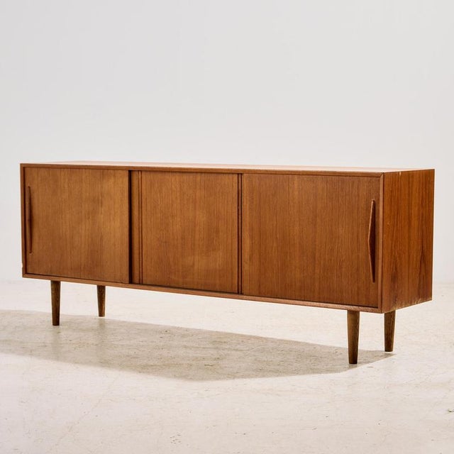 Danish teak sideboard from the 1960s with unique handles, three sliding doors and one shelf inside. The surface of the...