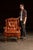 Tufted leather wingback armchair in a rich burnt amber hue, featuring brass nailhead trim and cabriole front legs. The...