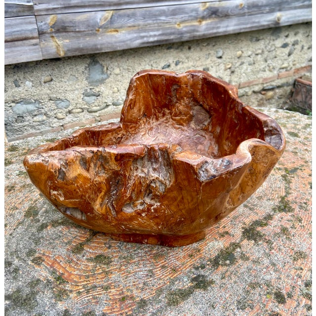 A striking sculptural bowl hand-carved from a single block of olive wood, showcasing a rich and expressive grain with...