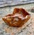 A striking sculptural bowl hand-carved from a single block of olive wood, showcasing a rich and expressive grain with...