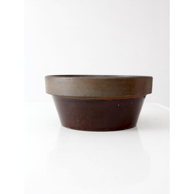 Antique American stoneware mixing bowl with a substantial rounded form, wide rolled rim, and rich brown glaze. Subtle...