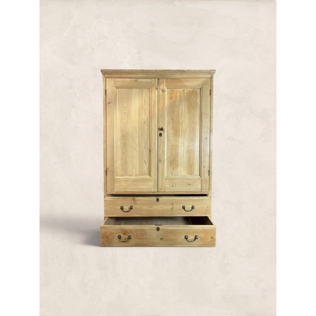 A beautiful antique English pine wardrobe dating to circa 1900, featuring a warm stripped pine finish, paneled double...