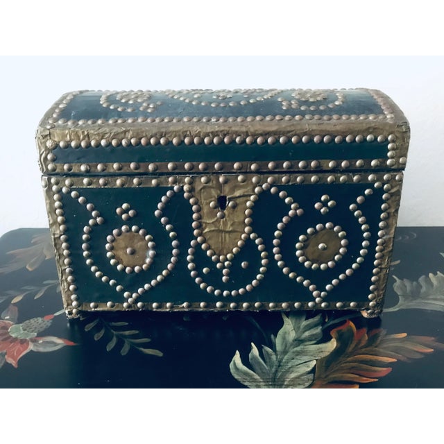 A stunning antique Spanish style wooden box wrapped in leather with tons of decorative studs depicting a beautiful flowing...