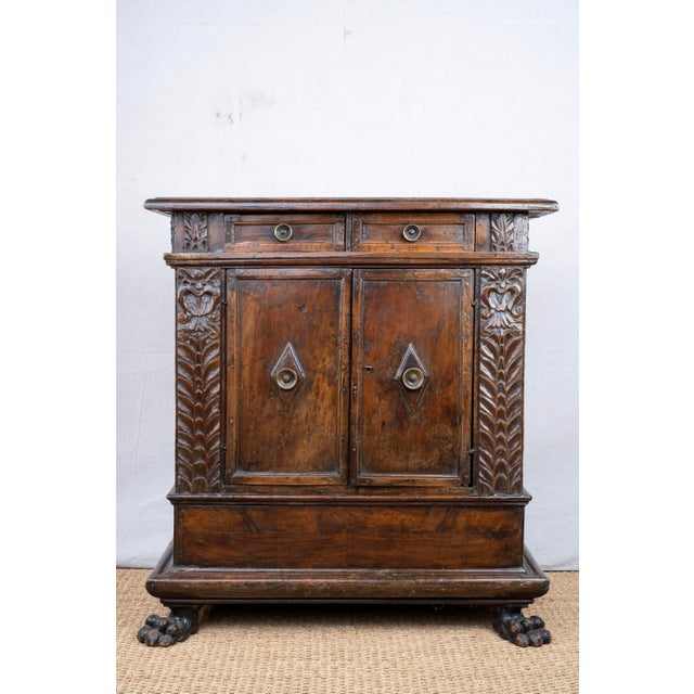 A carved oak cabinet, c. 1780, Italian. Features two drawers and a central cupboard framed by intricate carvings of...