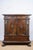 A carved oak cabinet, c. 1780, Italian. Features two drawers and a central cupboard framed by intricate carvings of...