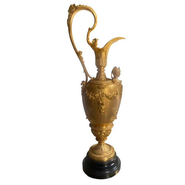 Elegant pair of late 19th century French gilt bronze decorative ewers, circa 1890s, raised on black marble bases. Each...