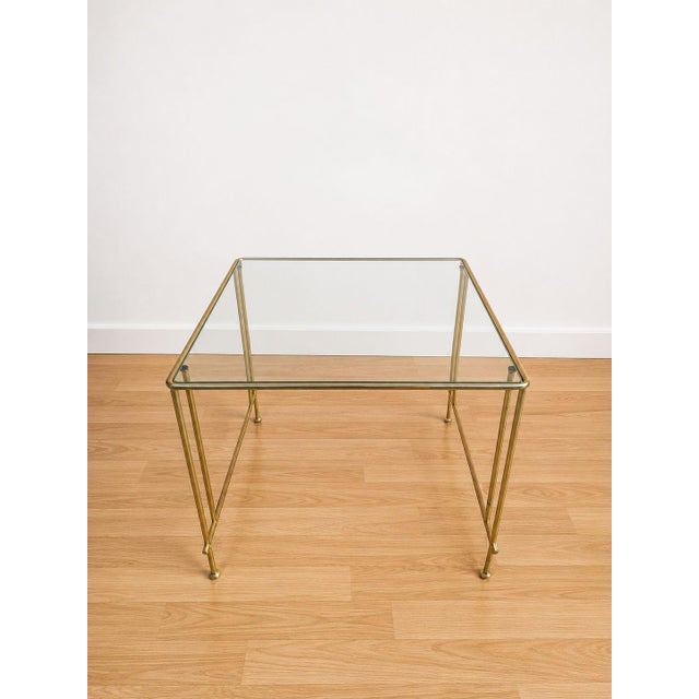 Elegant vintage Italian-made side table dating back to the 1960s, featuring a geometric polished brass frame with double...