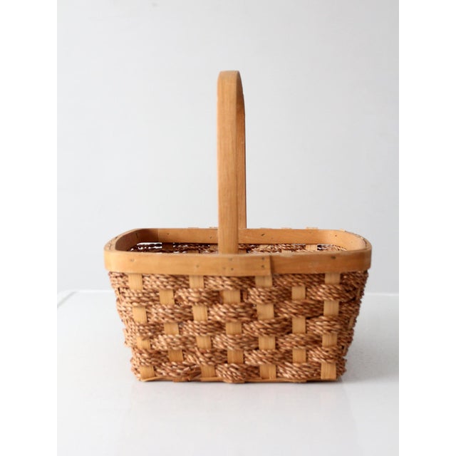 This vintage woven basket features a rectangular splint frame interwoven with twisted natural fiber and a tall bentwood...