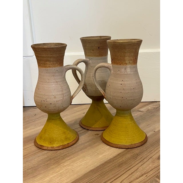 These mid-century style stoneware goblets feature a distinct tri-color glaze with a yellow pedestal base, a light grey or...