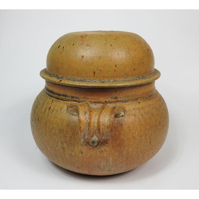 Mid 20th century studio stoneware pottery covered storage jar. Domed lid, hand pulled handles, matte ochre glaze with...