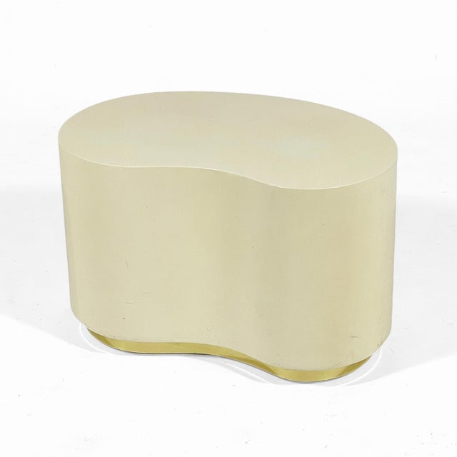 This pretty side table in the manner of Karl Springer has a kidney shape and inset brass plinth base which supports the...