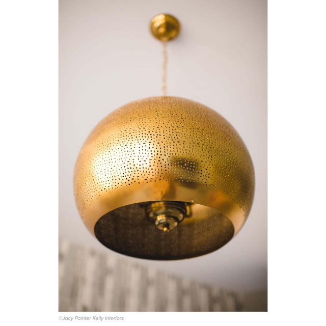 Handcrafted with a brilliant natural brass finish and an organic perforated design this pierced metal sphere pendant is...