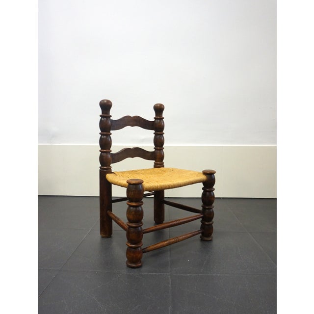 Low fireplace chair in turned wood with a rush seat. A mid-20th-century French handcrafted piece in the style of French...