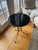 A small, French Maison Jansen style gueridon side table with a black marble top and circular tripodal pedestal iron base....